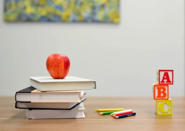An apple on a stack of notebooks