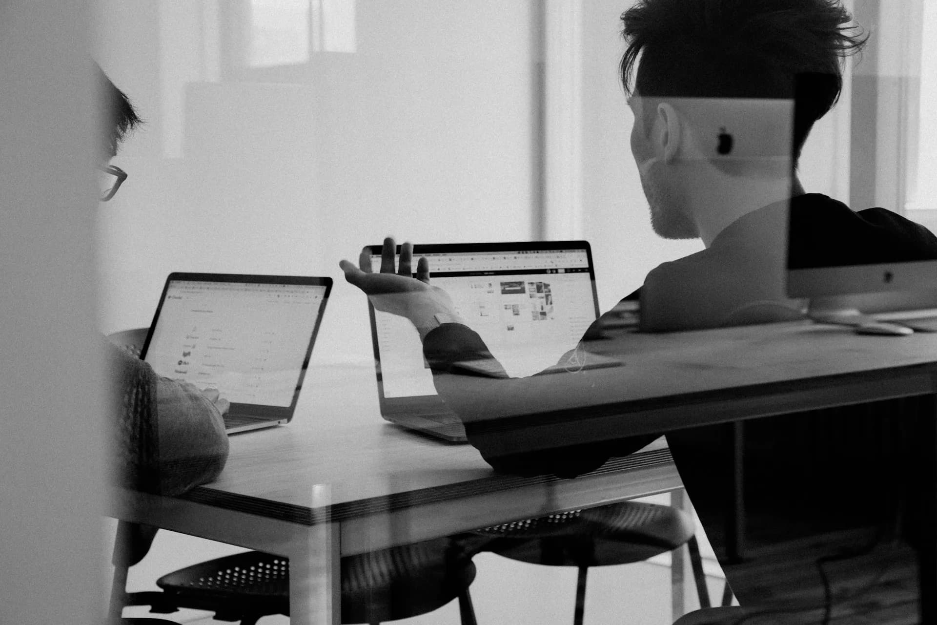 A black and white photo of a meeting room with people engaging in a remote meeting